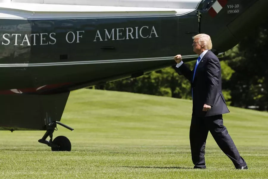 U.S. President Donald Trump pumps his fist at his aides and staff members looking on as he departs to spend the weekend at his New Jersey golf estate from the South Lawn of the White House.