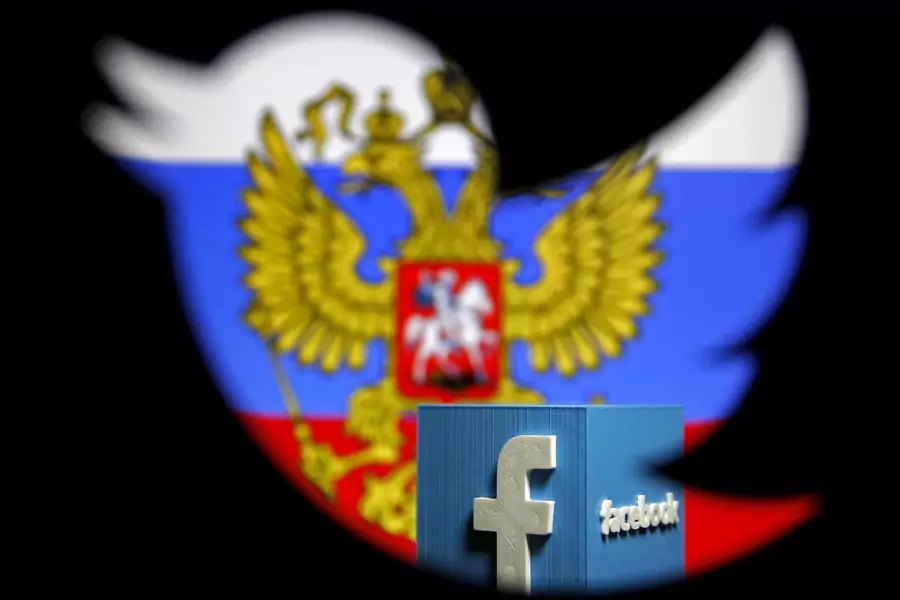 A Russian flag and a 3D model of the Facebook logo is seen through a cutout of the Twitter logo in a photo illustration.