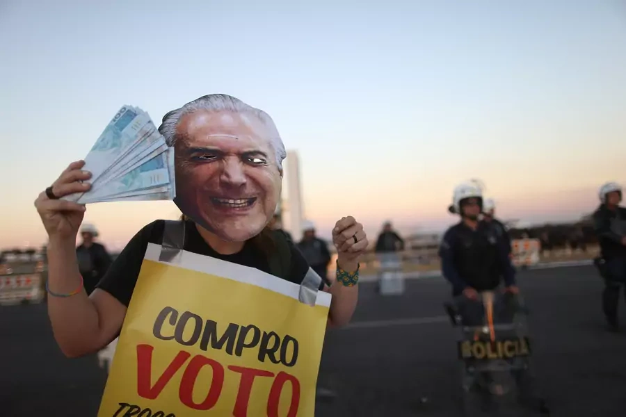 A demonstrator protests with a face mask of Brazil's President Michel Temer during a vote on sending corruption charges against Temer to the Supreme Court for trial in Brasilia. 