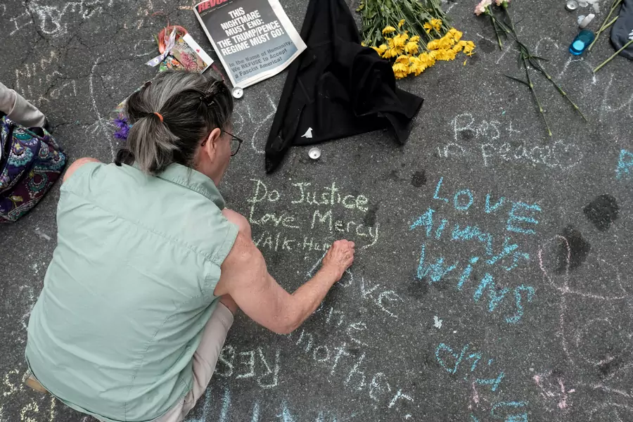 A woman writes a message on the street commemorating the victims at the scene of the car attack on a group of counter-protesters during the "Unite the Right" rally in Charlottesville, Virginia on August 14, 2017.