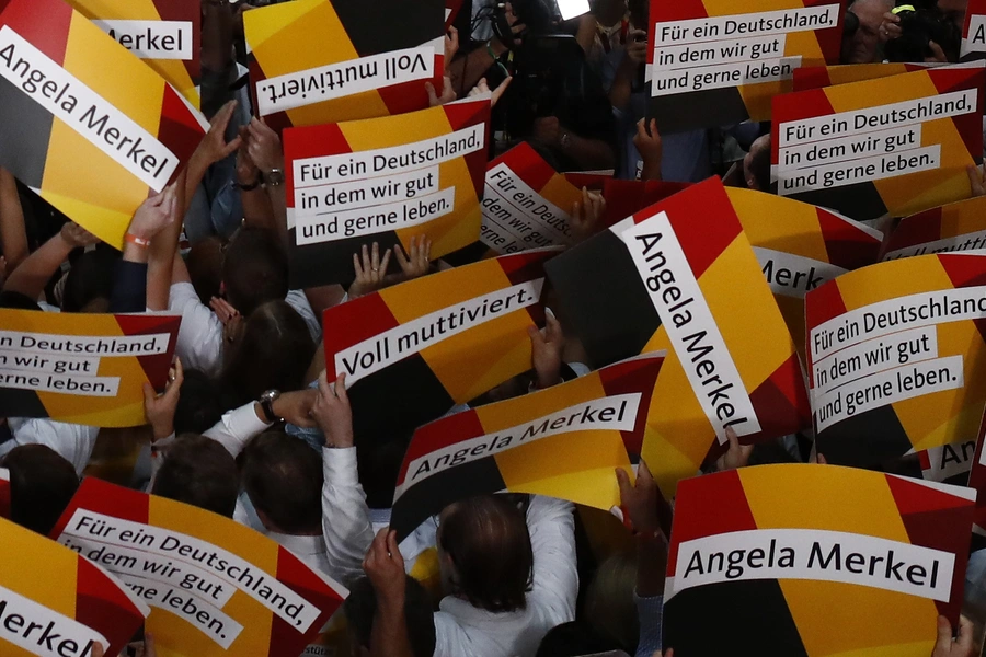 People hold placards while waiting for Christian Democratic Union CDU party leader and German Chancellor Angela Merkel to react on first exit polls in the German general election (Bundestagswahl) in Berlin, Germany. 