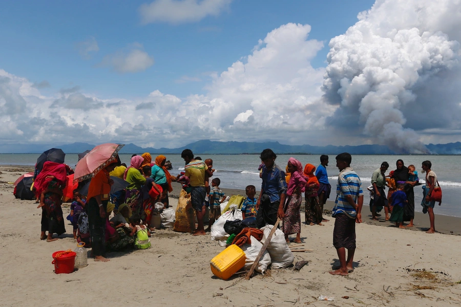 Rohingya refugees watch the smoke on Myanmar border side after crossing the Bangladesh-Myanmar border by boat through the Bay of Bengal, in Shah Porir Dwip, Bangladesh on September 11, 2017.