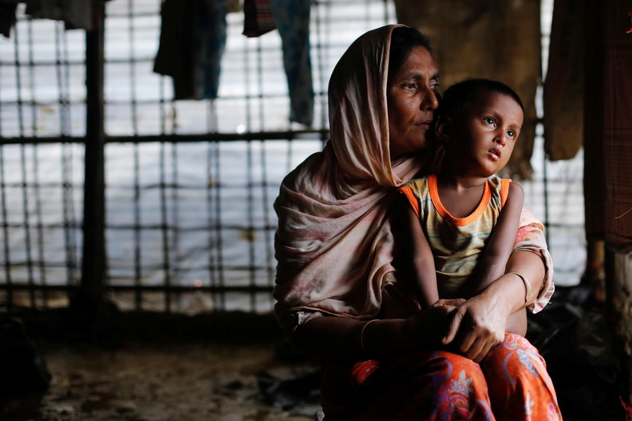 A Rohingya refugee woman waits for aid with her grandson inside their temporary shelter at a camp in Cox's Bazar, Bangladesh September 19, 2017. 