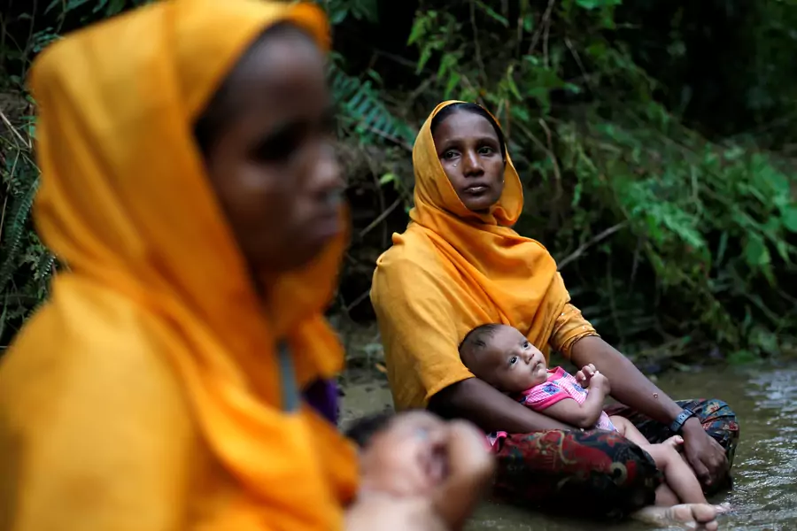 Rohingya women sit with infants by a river near Cox Bazaar, a sprawling refugee camp for Rohingya Muslim minorities fleeing attacks on villages and sexual violence in Myanmar.