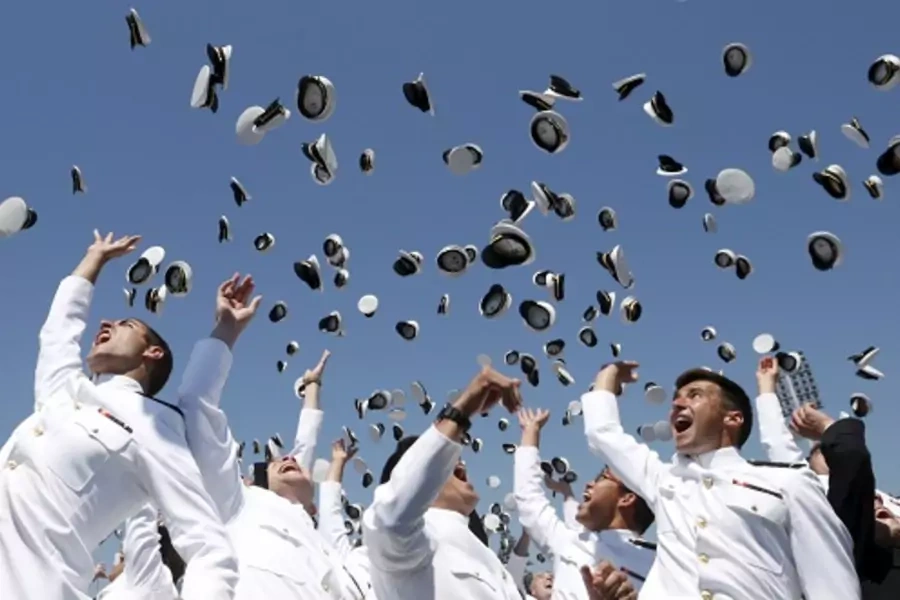 U.S. Naval Academy graduates toss their caps in the air. 