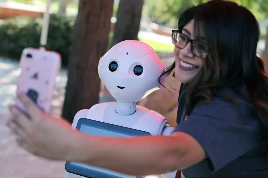 A student takes a selfie with "Pepper" an artificial Intelligence project utilizing a humanoid robot from French company Aldebaran. 