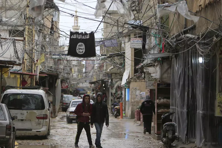 Youth walk under an Islamic State flag in Ain al-Hilweh Palestinian refugee camp, near the port-city of Sidon, southern Lebanon January 19, 2016.