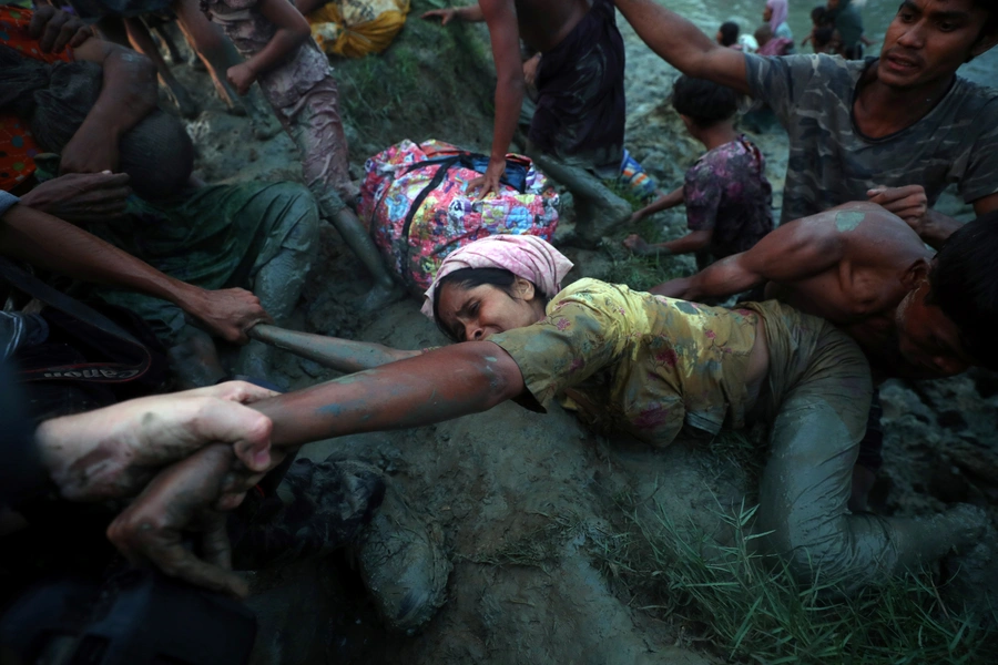 Photographers help a Rohingya refugee to come out of Naf River as they cross the Myanmar-Bangladesh border in Palong Khali, Bangladesh on November 1, 2017.