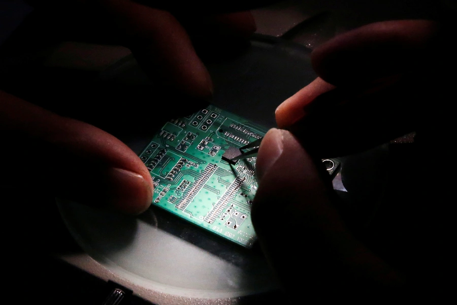 A researcher plants a semiconductor on an interface board which is placed under a microscope during a research work to design and develop a semiconductor product at Tsinghua Unigroup research centre in Beijing, China.