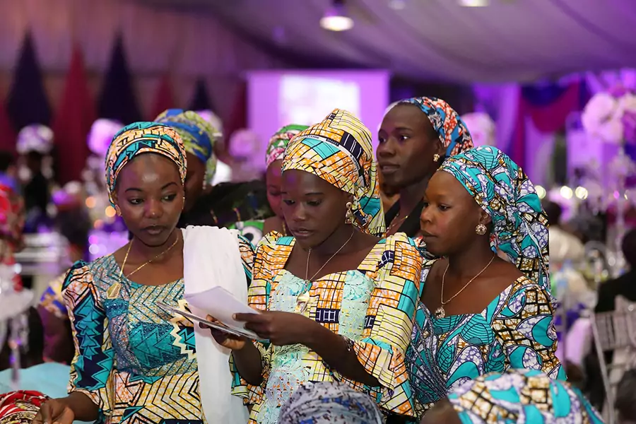 Some of the 106 girls who were kidnapped by Boko Haram militants in the Nigerian town of Chibok look through a set of photographs during the the send-forth dinner organised for them in Abuja, Nigeria September 13, 2017.