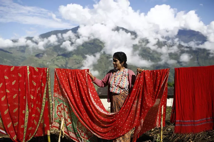 Devi Budhathoki, 38, dries her clothes outside her house in Kharay, Dolkha District.
