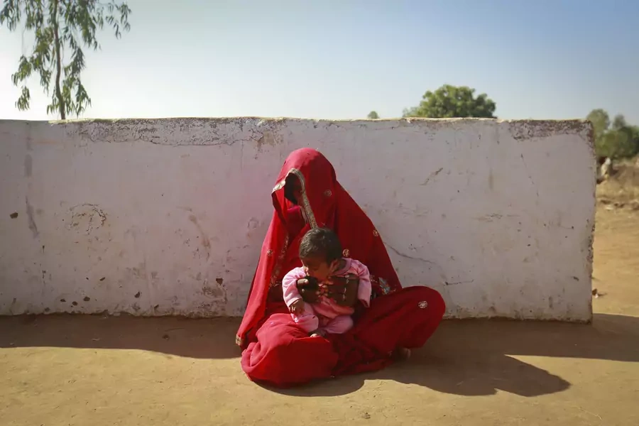 Krishna, 14, sits with her four-month-old baby Alok outside her house in a village near Baran, located in the northwestern state of Rajasthan, January 21, 2013. Krishna was married to her husband Gopal when she was 11 and he was 13. 