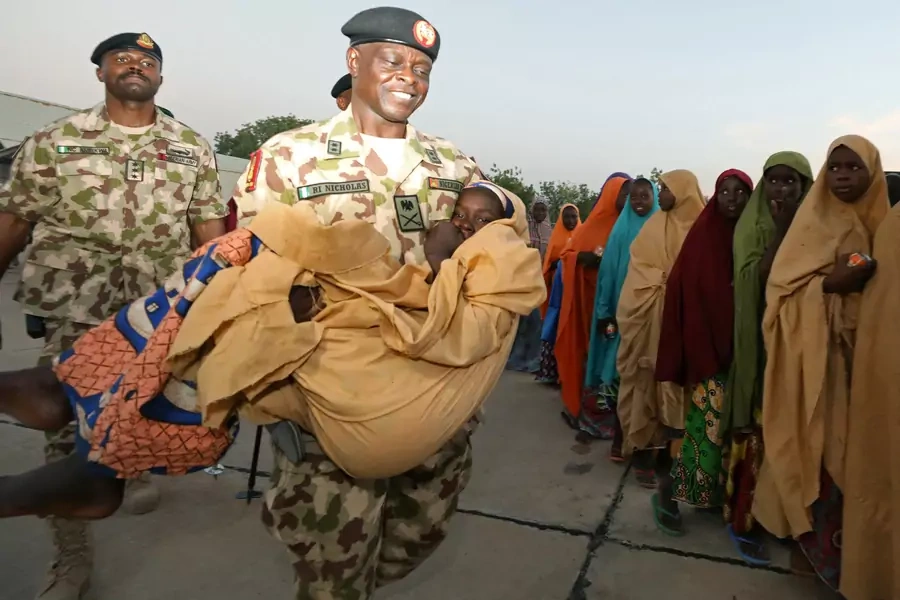 Major General Rogers Nicholas, Theatre commander, Operation Lafiya Dole, carries one of the newly released Dapchi schoolgirls as others wait for boarding a plane at the air force base in Maiduguri, Nigeria March 21, 2018. 