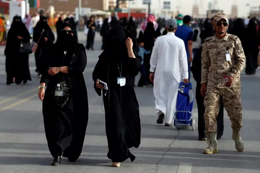 Women pass by a member of Saudi security forces at the Janadriyah Cultural Festival on the outskirts of Riyadh, February 12, 2018. The Saudi government recently announced that women will be allowed to join the country’s armed forces.