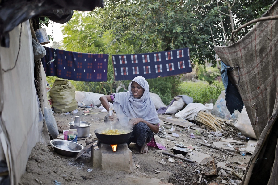 A woman from the Rohingya community from Myanmar cooks food outside her makeshift shelter in a camp in New Delhi, September 13, 2014.