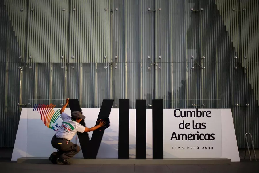A woman cleans a banner ahead of the eighth Summit of the Americas in Lima, Peru April 10, 2018. 