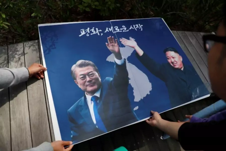 Students hold posters with pictures of South Korea's President Moon Jae-in and North Korea's leader Kim Jong Un during a pro-unification rally ahead of the upcoming summit between North and South Korea in Seoul, South Korea April 26, 2018.