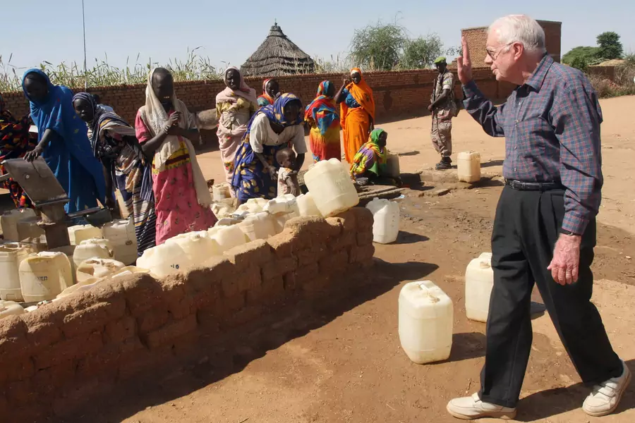 Former U.S. President Jimmy Carter waves to internally displaced women at a water point in Kebkabiya town in North Darfur October 3, 2007. Carter began his fight against Guinea worm in 1986.