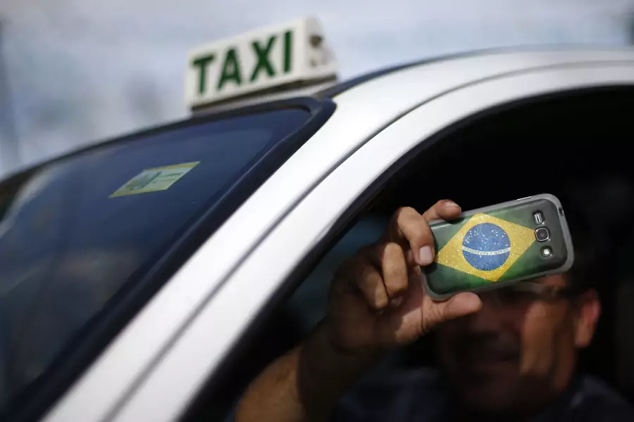 A taxi driver takes photos at the slum of Varjao on the outskirts of Brasilia in 2014.