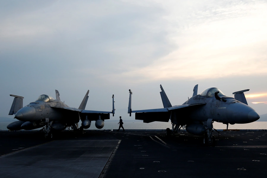 A sailor walks behind aircraft on the U.S. Navy carrier USS Carl Vinson after it docked at a port in Danang, Vietnam, on March 5, 2018