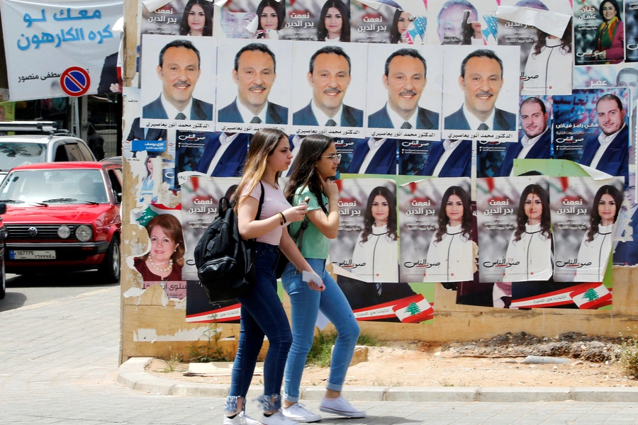 Girls walk past pictures of Lebanese parliament candidates in Beirut.