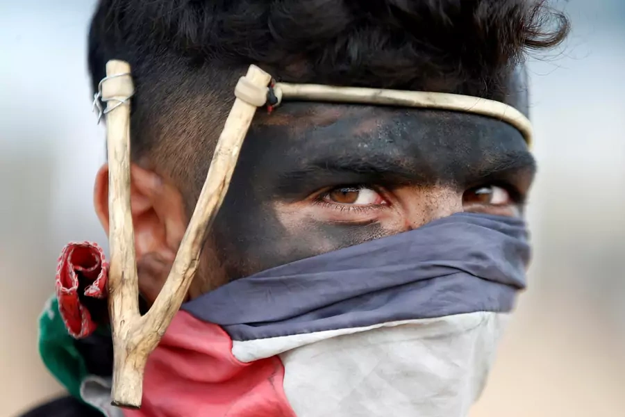A Palestinian demonstrator with a slingshot looks on during a protest against U.S. embassy move to Jerusalem and ahead of the 70th anniversary of Nakba, at the Israel-Gaza border, east of Gaza City. May 14, 2018.