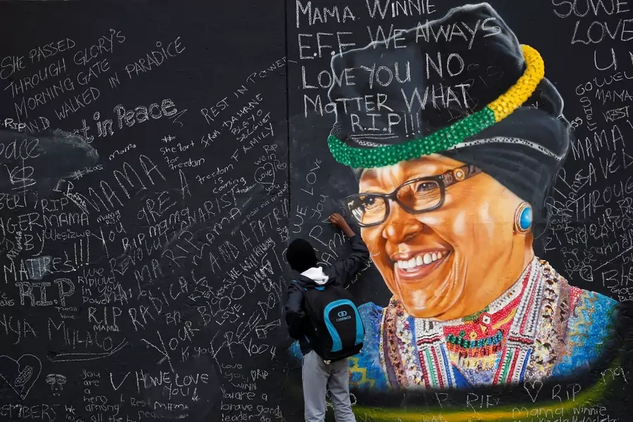 A boy returning from school writes a message on a wall with a mural of the late Winnie Madikizela-Mandela, painted by Inqubeko communications, in Soweto, South Africa, April 13, 2018.