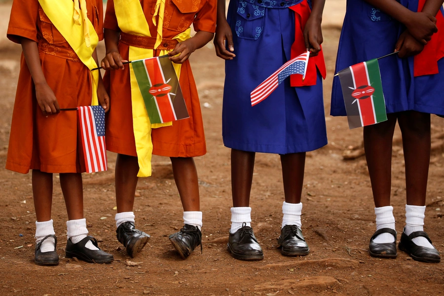 Girls with U.S. and Kenya flags wait to greet U.S. Ambassador to Kenya as he visits a President's Emergency Plan for AIDS Relief (PEPFAR) project for girls' empowerment in Nairobi, Kenya.