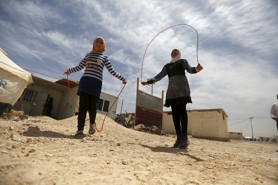 Syrian refugee Omayma al Hushan (R), 14, who launched an initiative against child marriage among Syrian refugees, plays with her friend outside their residence in Al Zaatari refugee camp.