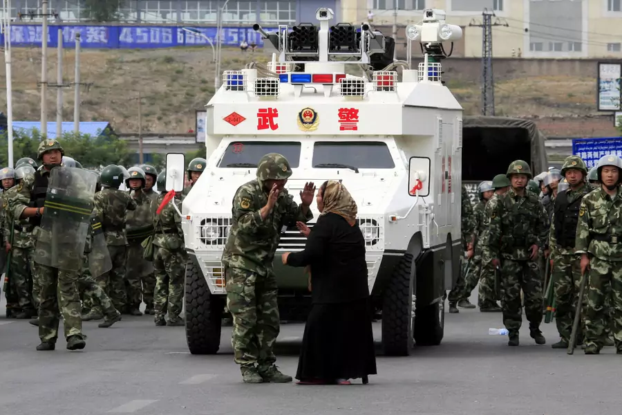 A woman on a crutch argues with a Chinese paramilitary police in front of an armoured personnel carrier in the city of Urumqi in China's Xinjiang Autonomous Region in 2009.