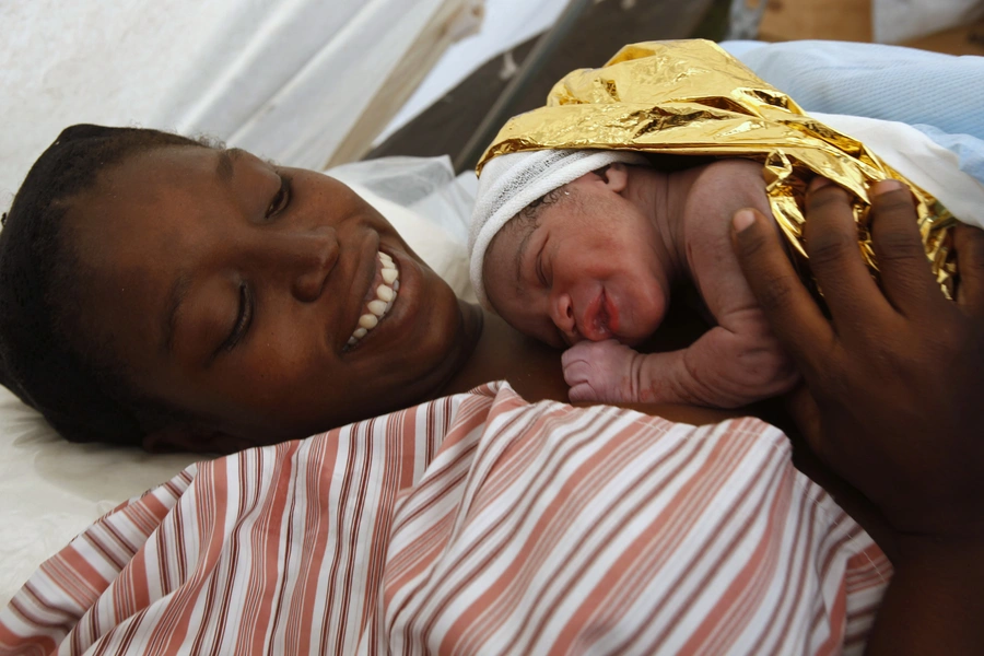 Madame Marcus holds her five-minute-old baby boy after giving birth to her second child at a makeshift hospital run by B-FAST (Belgian First Aid and Support Team).