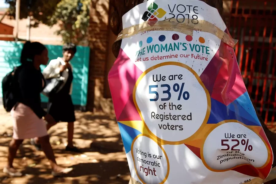 Women walk past Zimbabwe Electoral Commission (ZEC) posters in Harare, Zimbabwe, July 26, 2018. 
