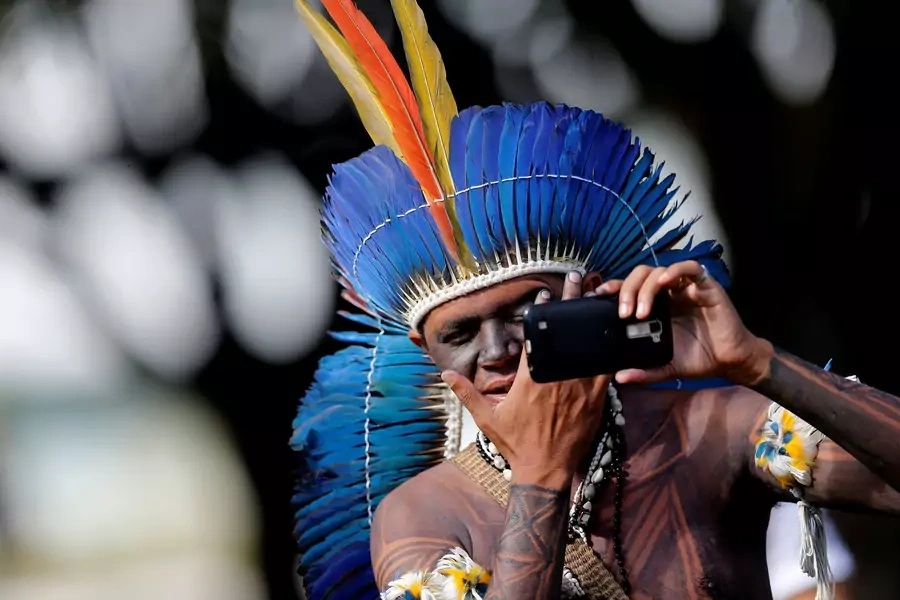 A Brazilian Indigenou checks his face in a mobile phone at the Terra Livre camp, or Free Land camp in Brasilia, Brazil on April 23, 2018