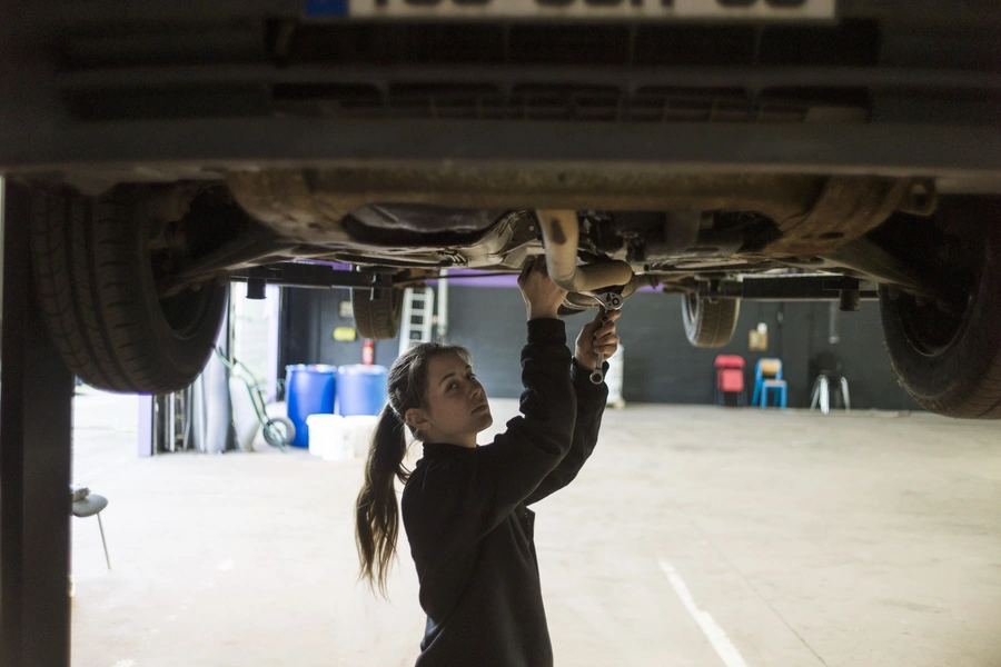 A woman mechanic works on a car in an innovative garage and auto repair workshop that is catering exclusively to female customers, in Saint-Ouen-l'Aumone, in the suburbs of Paris. May 14, 2014. 