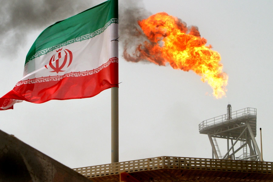 A gas flare on an oil production platform in the Soroush oil fields is seen alongside an Iranian flag in the Persian Gulf, Iran, July 25, 2005.