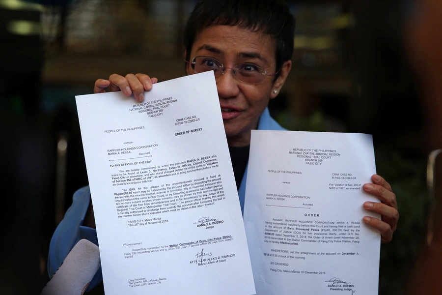 Maria Ressa, an executive of online news platform Rappler, shows her arrest warrant and release order after posting bail for tax evasion charges at Regional Trial Court Branch 265 in Pasig City, Metro Manila, in Philippines, on December 3, 2018.