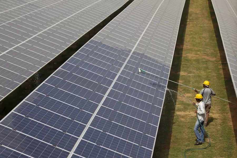 Workers clean photovoltaic panels inside a solar power plant in Gujarat, India.