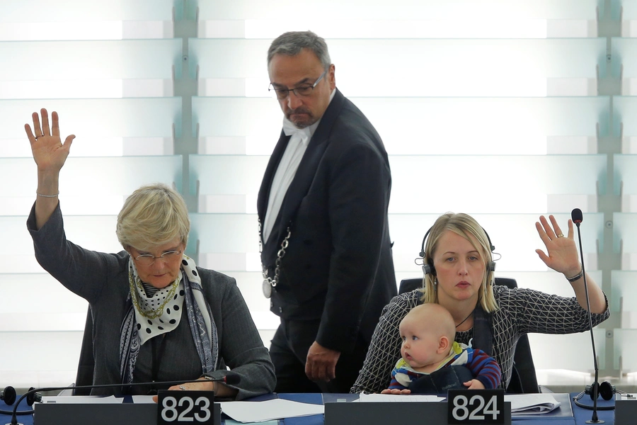 Swedish Member European Parliament Jytte Guteland (R) holds her baby as she takes part in a voting session at the European Parliament.