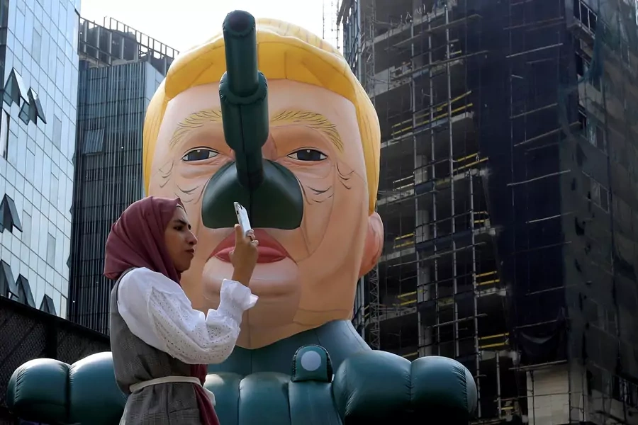 A woman stands next to an inflatable tank with U.S. President Donald Trump outside an art exhibition 'MonuMental' by the pseudonymous artist, Saint Hoax in downtown Beirut, Lebanon October 12, 2018. 