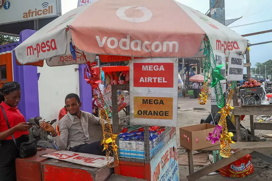 A vendor assists a client to recharge her cell phone airtime at an open air stall in Kinshasa, Democratic Republic of Congo, on January 1, 2019.