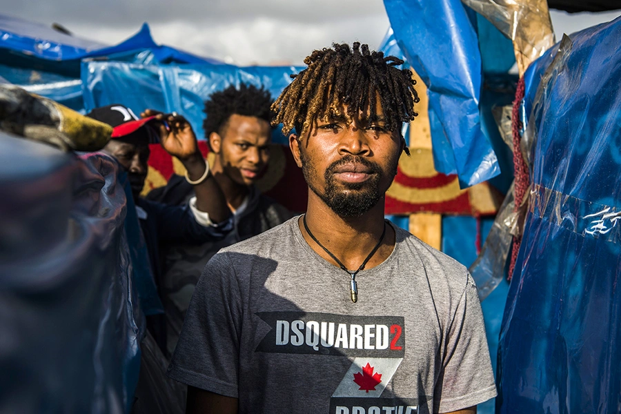 A sub-Saharan migrant walks between make-shift tents in the Oulad Ziane migrant camp in Casablanca on March 27, 2019.