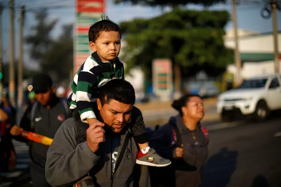 Father and son walk in a caravan of migrants en route to U.S. in San Salvador