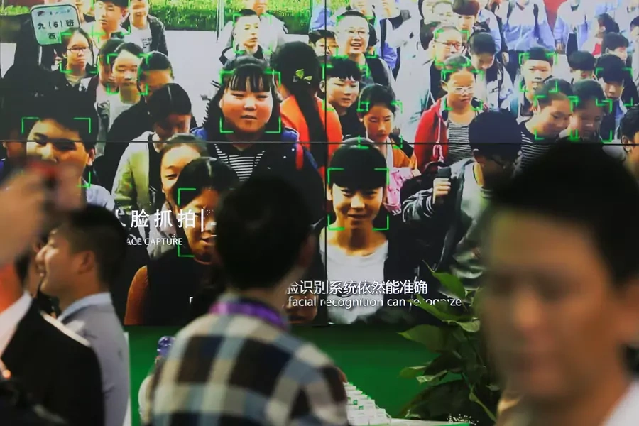 Visitors walk past a screen showing a demonstration of facial recognition software at the Security China 2018 exhibition on public safety and security in Beijing, China October 23, 2018
