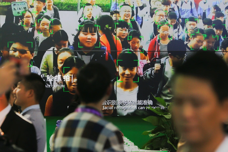 Visitors walk past a screen showing a demonstration of facial recognition software at the Security China 2018 exhibition on public safety and security in Beijing, China October 23, 2018