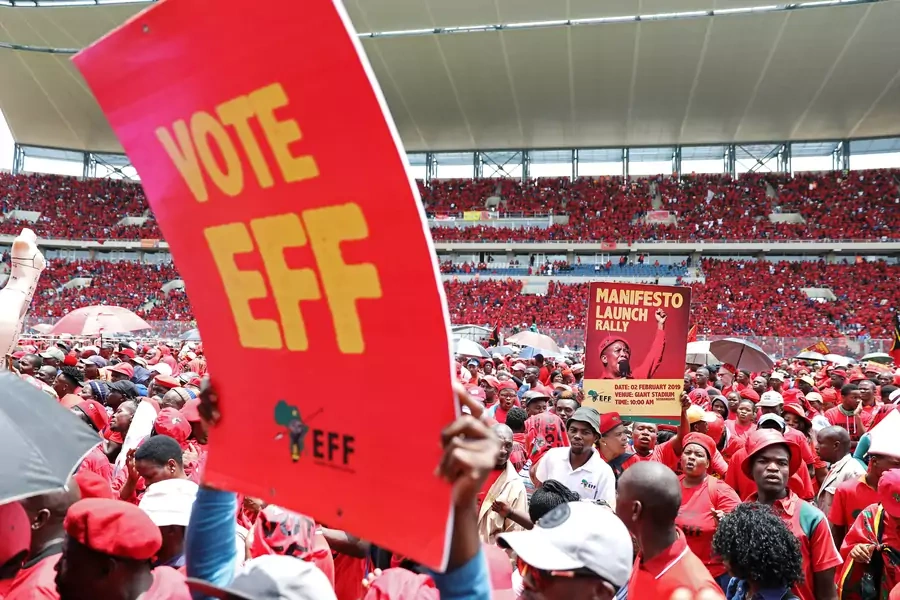 Supporters of South Africa's radical left-wing party, the Economic Freedom Fighters (EFF), hold a placard during the launch of the party's election manifesto in Soshanguve, near Pretoria, South Africa, on February 2, 2019. 