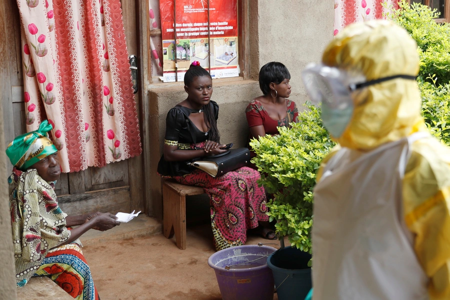 Women sit as healthcare workers enter a room where is a baby suspected of dying of Ebola in Beni, North Kivu Province of Democratic Republic of Congo, on December 13, 2018.