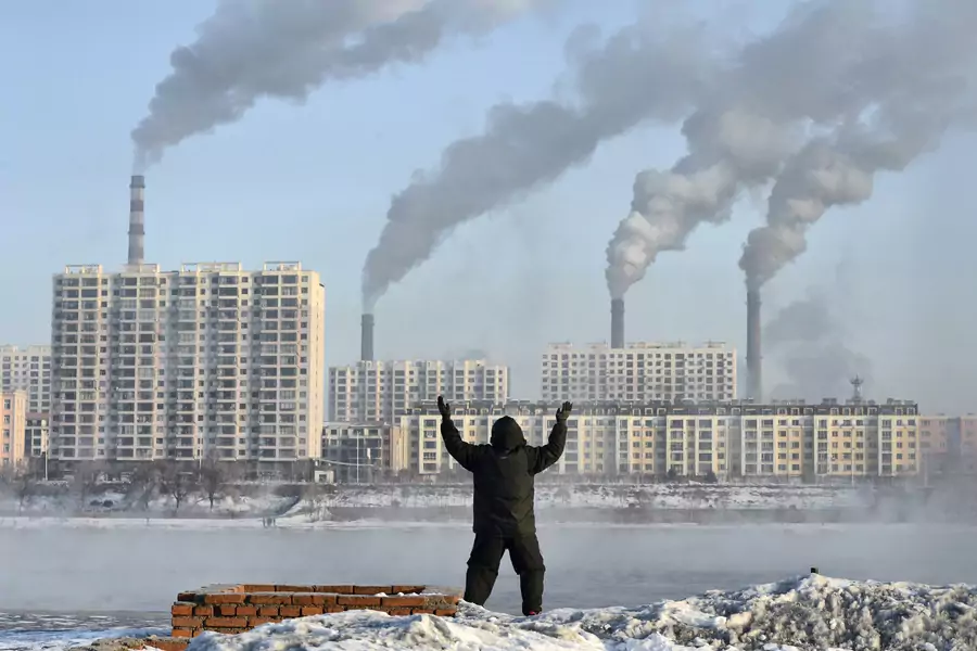 An elderly man exercises in the morning as he faces chimneys emitting smoke behind buildings across the Songhua river in Jilin province, China on February 24, 2013