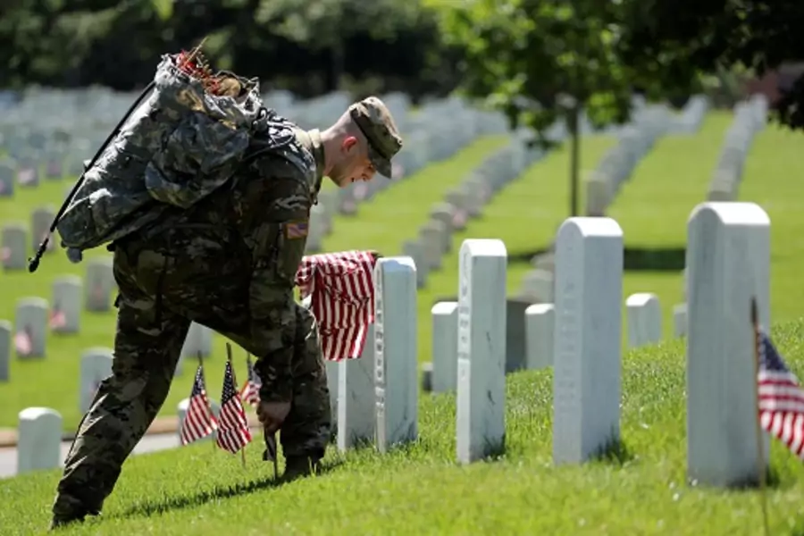 U.S. Army soldiers of the 3rd United States Infantry Regiment place U.S. flags on graves at Arlington National Cemetery, U.S. May 24, 2018. 