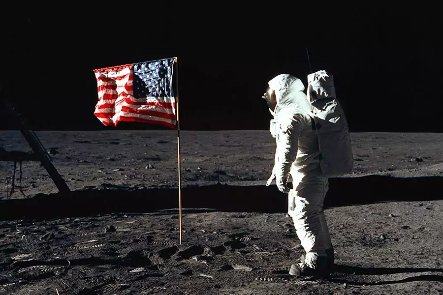  Astronaut Edwin E. Aldrin Jr., lunar module pilot of the first lunar landing mission, poses for a photograph beside the deployed U.S. flag on the lunar surface. 