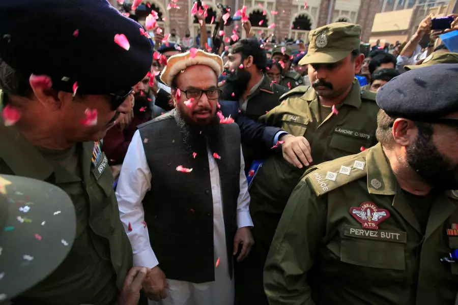 File photo: Supporters shower Hafiz Saeed with flower petals as he walks to court in Lahore, Pakistan, in November 2017. The court released him from house arrest.